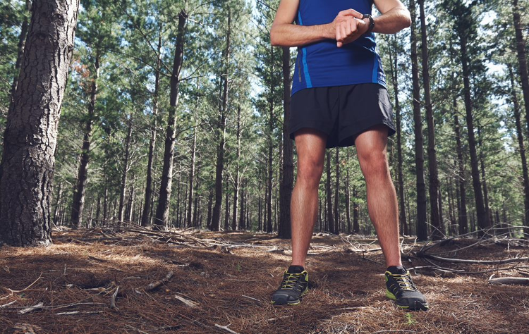 Training while working from home: a runner in a woodland pauses to check his watch