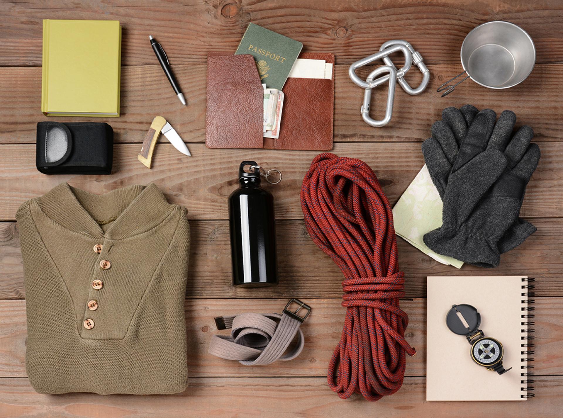 Kit for a walking holiday laid out on a table, including water bottle, spare shirt and gloves