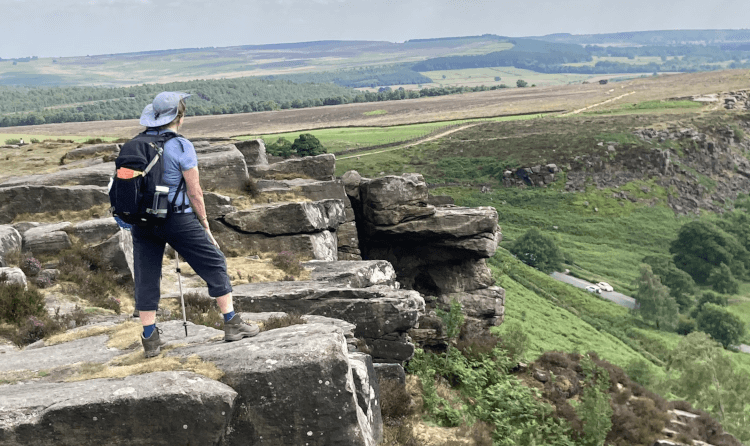 A walker on a multi-day hike looks out over challenging terrain, carrying only a small rucksack.