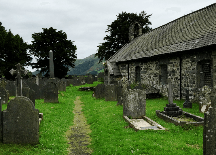 A pathway leads between graves and the stone side of St Mary's Church