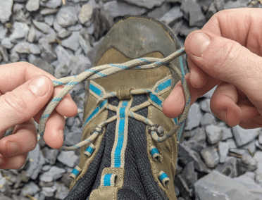 A starting knot displayed on a walking boot. This is the simple knot you tie when securing your shoes, just before the bow.