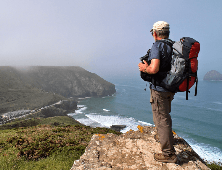 A walker looks down over the ocean near Port Isaac.