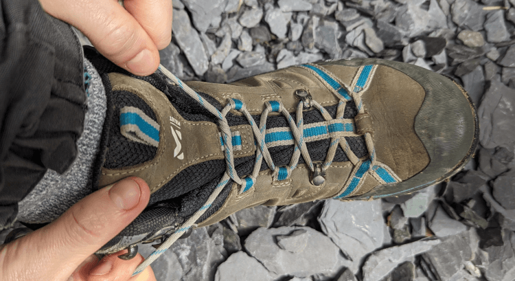 A walker secures the looser lacing over her forefoot and toes with a double starting knot or surgeon's knot.