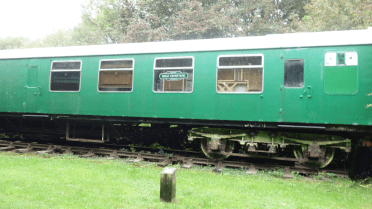 Bright green decommissioned train carriages stand beside the Downs Link trail.