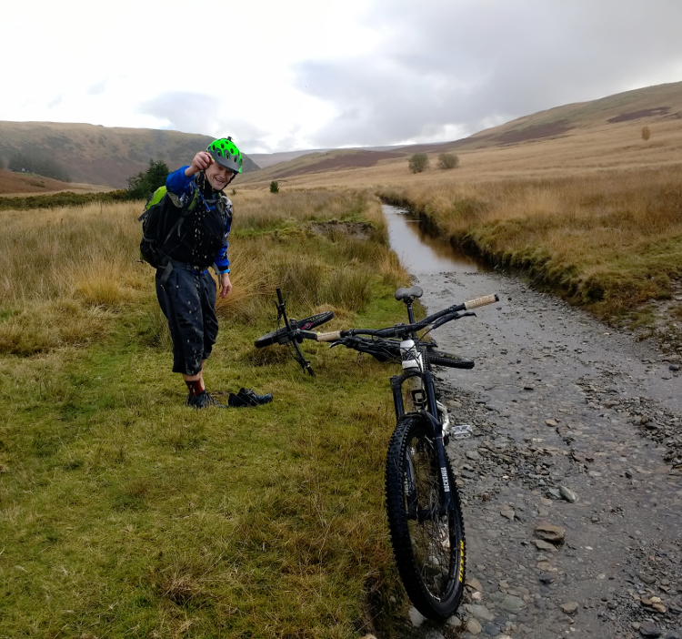 A cyclist stops to squeeze out a sock after a particularly wet section of the Trans Cambrian Way