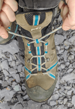 The hiker has passed the painful part of her instep with vertical lacing and pulls the laces back into the usual crossover lacing pattern.