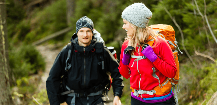 Two walkers demonstrate layering techniques, with visible waterproofs, hats, gloves, midlayers and baselayers - exactly what a beginner is looking to learn.