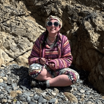 Vicki, tour pack administrator, sits cross-legged at the beach.