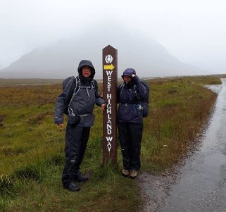 The mizzle comes down on a pair of walkers celebrating another stage of their West Highland Way walk.