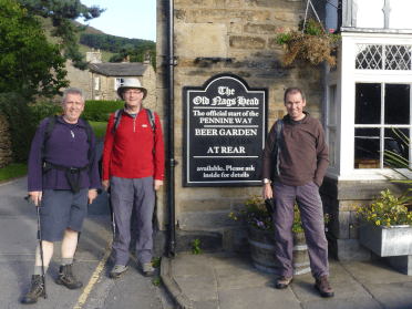 Three walkers posed together outside the Nags Head pub at the start of the Pennine Way in Edale.