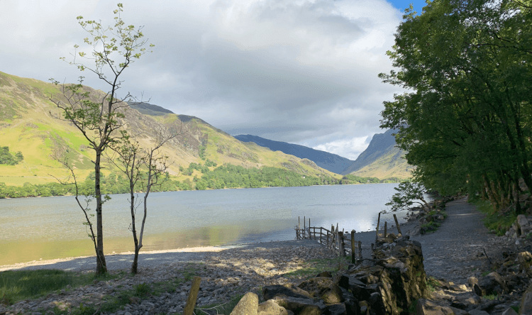 Lake District fells in the background, Buttermere in the foreground, encircled by a winding path between trees on the shore: this is Buttermere Circuit, one of the five best waterside walks in the Lake District.