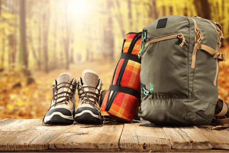 Equipment for a holiday laid out: hiking boots, a pad for sitting on and a well-packed rucksack.