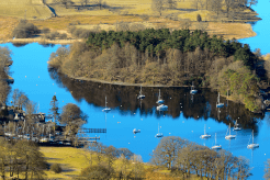 An aerial shot of the blue waters of Windermere, populated by white sailboats.