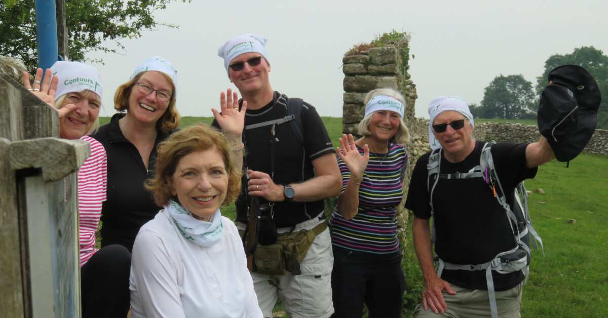 A large group of walkers gather for a photo on a multi-day walk in the countryside.