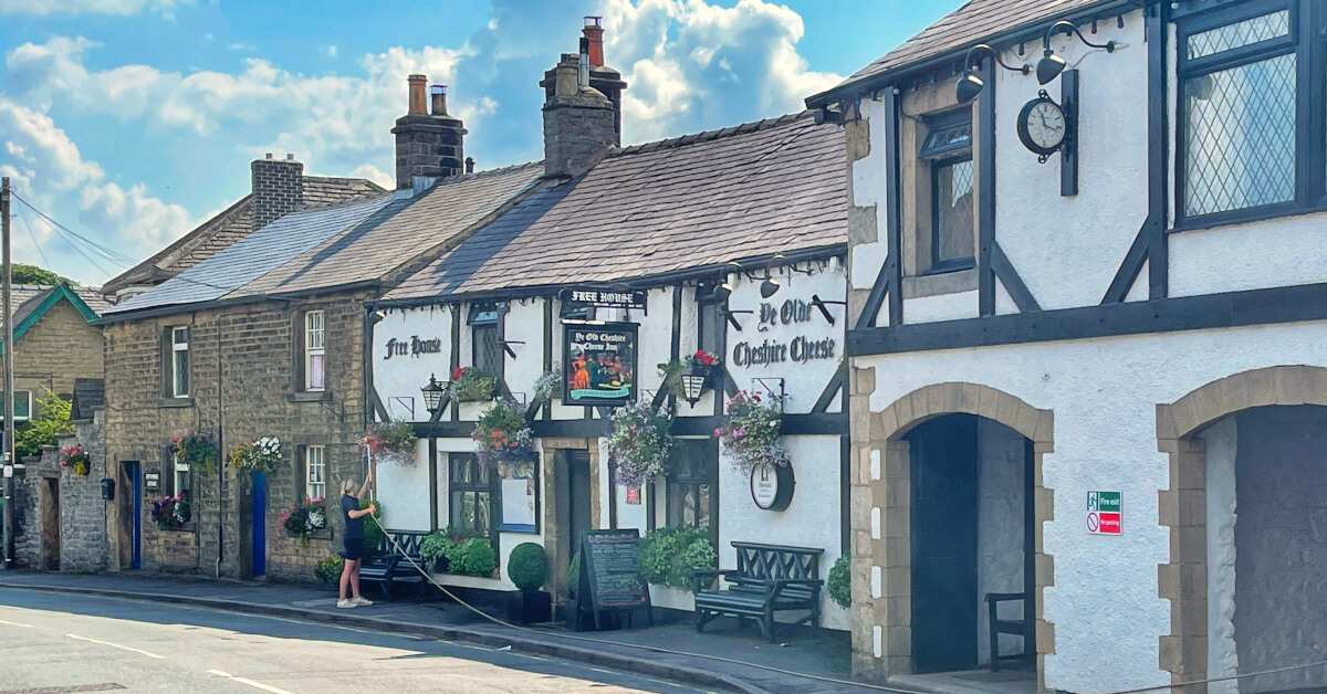 Ye Olde Cheshire Cheese Inn, a traditional black-and-white pub decorated with brightly coloured hanging baskets, sits in Castleton near the Mam Tor and Great Ridge Walk.