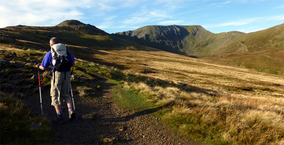 A male hiker utilises poles while hillwalking in the UK.