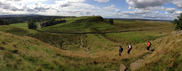 Walkers cross a wide, undulating field on an A to B walking holiday.